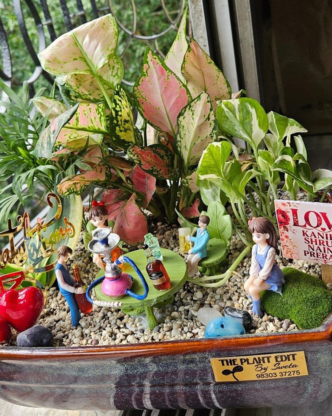 A custom-made planter built around personal objects and photographs, planted with green foliage.