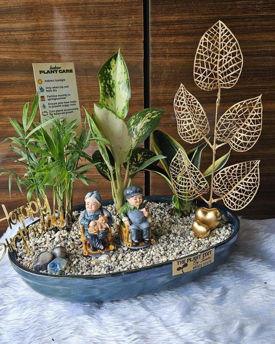 A restrained planter with brass leaf forms rising above pale gravel.