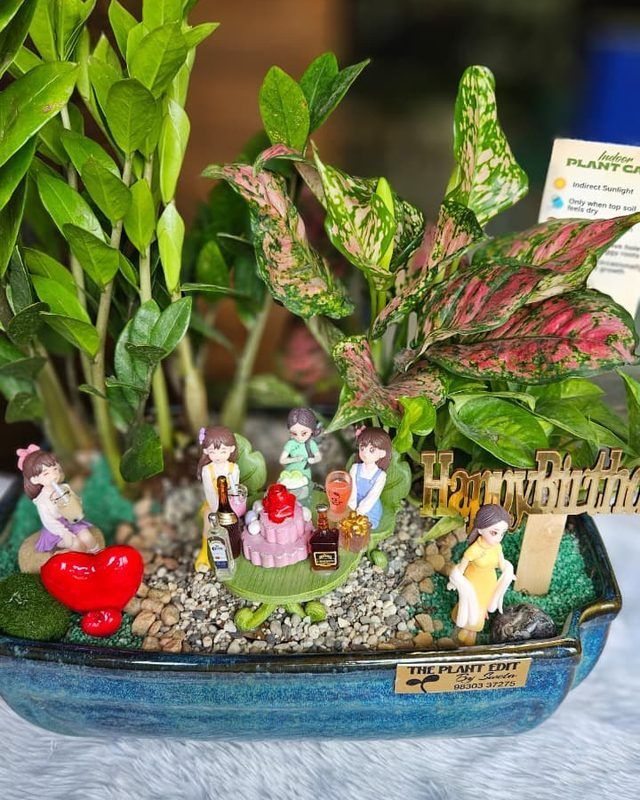 A bright birthday planter crowded with small celebrating figures.