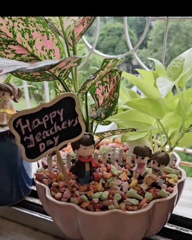 A Teachers' Day planter with a small chalkboard message on a sunlit windowsill.